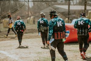 Men in paintball gear strategizing on a sunny day outdoors.